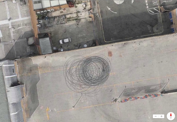A Google maps view of the left over tyre tracks artwork on top of a car park in Peckham london. Taken by chance by satellite mapping systems, Google and apple maps